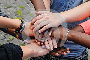 Multiracial teen friends joining hands together in cooperation