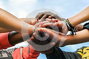 Multiracial teen friends joining hands together in cooperation photo
