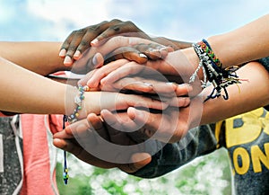 Multiracial teen friends joining hands together in cooperation photo