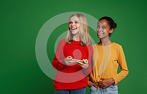 Multiracial two girls laughing together while using cellphones