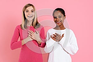Multiracial two girls smiling while holding hands on their chests