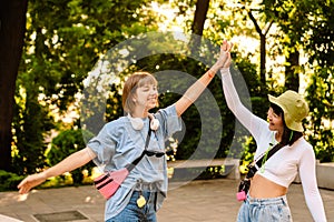 Multiracial two women smiling and giving high five while walking in park