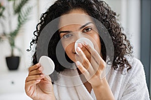 Multiracial woman removing cosmetics from nose area
