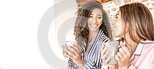 Multiracial women couple smiling looking each other holding a teacup in pajama just waken up. New normal gay families relationship