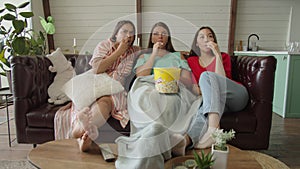 Multiracial women expressing fright by scary scene of film indoors