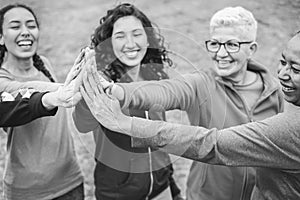 Multiracial women stacking hands outdoor at city park - Main focus on african female hand