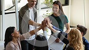 Multiracial workers with female leader, coach giving high five.