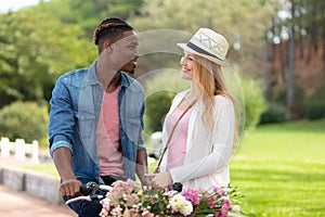 multiracial young couple with bicycle with flowers in basket