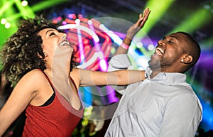 Multiracial young couple dancing at night club with laser light show