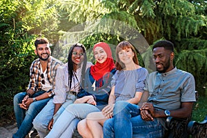 Multiracial young friends sitting by the street and having fun