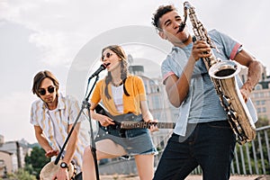 Multiracial young people with guitar djembe and saxophone performing photo