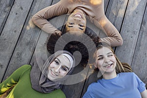 Multiracial young teen female friends resting in the park after sport training laughing and having fun together