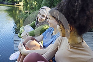 Multiracial young teen female friends resting in the park after sport training laughing and having fun together