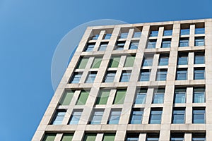 Multistorey building standing against blue sky background. Bottom view of modern.