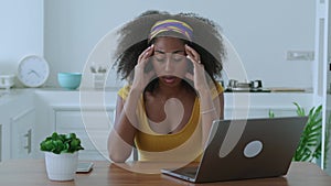 Multitasking African American woman, entrepreneur having headache due to computer stress after hard work on new business