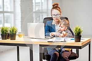 Multitasking businesswoman with her son working at the office