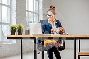 Multitasking businesswoman with her son working at the office