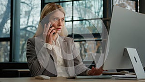 Multitasking female office worker Caucasian middle-aged adult woman typing computer talk mobile phone discuss business