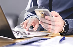 Multitasking and mobile technology. Busy workaholic business man using phone and laptop. Entrepreneur working hard with smartphone photo