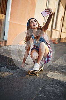 Multitasking the skatter way. Shot of a carefree young woman riding low on a skateboard while taking a self portrait