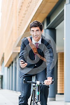 Multitasking young businessman riding a bicycle to work