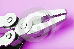 Multitool is a multi-functional tool on a pink background. The concept of an open, flying multi-tool with free space