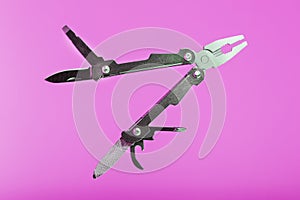 Multitool is a multi-functional tool on a pink background. The concept of an open, flying multi-tool with free space