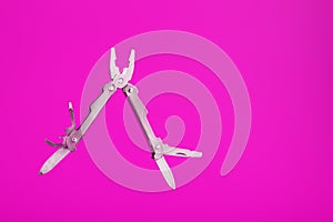 Multitool is a multi-functional tool on a pink background. The concept of an open, flying multi-tool with free space