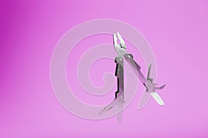 Multitool is a multi-functional tool on a pink background. The concept of an open, flying multi-tool with free space