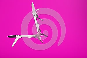 Multitool is a multi-functional tool on a pink background. The concept of an open, flying multi-tool with free space