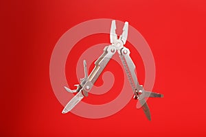 Multitool is a multi-functional tool on a red background. The concept of an open, flying multi-tool with free space