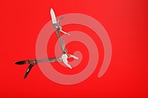 Multitool is a multi-functional tool on a red background. The concept of an open, flying multi-tool with free space