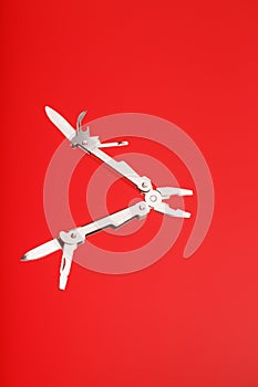 Multitool is a multi-functional tool on a red background. The concept of an open, flying multi-tool with free space