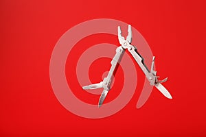 Multitool is a multi-functional tool on a red background. The concept of an open, flying multi-tool with free space