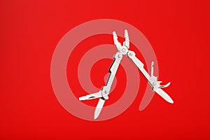 Multitool is a multi-functional tool on a red background. The concept of an open, flying multi-tool with free space