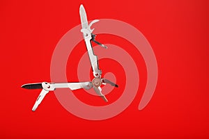 Multitool is a multi-functional tool on a red background. The concept of an open, flying multi-tool with free space