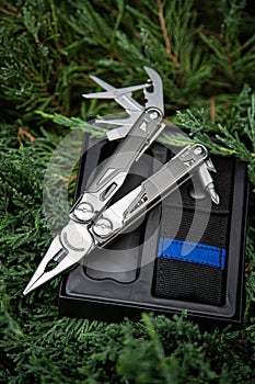 Multitool pocket knife in open case on greenery