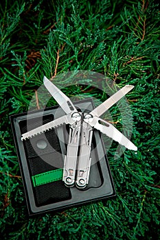 Multitool pocket knife in open case on greenery