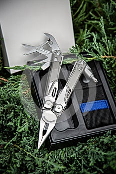 Multitool pocket knife in open case on greenery