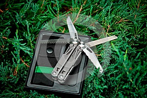 Multitool pocket knife in open case on greenery