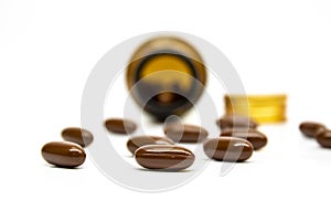Multivitamin softgel capsules droped out of container with white background and blurred container