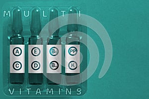 Multivitamins using concept. Four ampules with overlay letters of inscription A C E D K PP B6 B12 vitamin elements