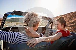 Mum and adult daughter in open top car, back view, close up