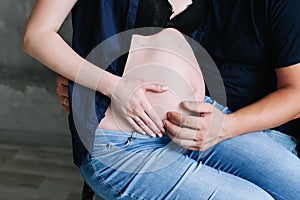 Mum and dad hold the pregnant belly. Beautiful tender mood photo of pregnancy.