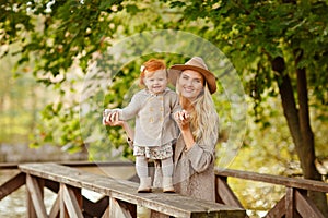 Mum gently embraces the redhead baby girl and laughing in autumn