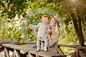 Mum gently embraces the redhead baby girl and laughing in autumn