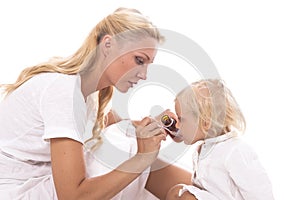 Mum giving a spoon of syrup to little girl