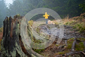 Mum and her little son go on a mountain trail in wet autumn weather. They are accompanied by a dog