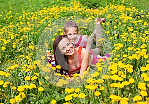 Mum and kid girl child among yellow flowers dandelions