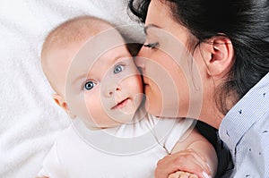 Mum kissing her son on a white bed